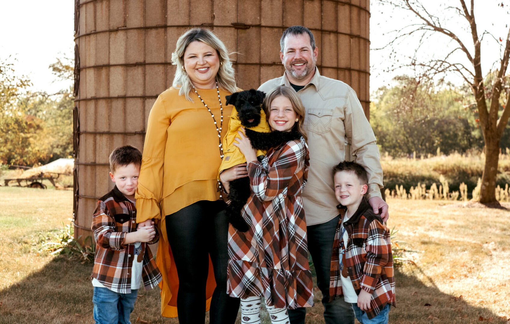 Family of five posing for a photo in front of a silo